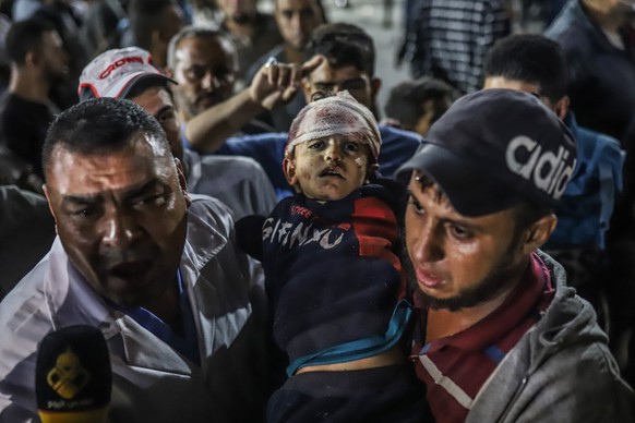 17.10.2023, Palästinensische Gebiete, Gaza-Stadt: Palästinenser tragen ein Kind aus dem Ahli Arab Krankenhaus in Richtung Al-Shifa Krankenhaus im Gazastreifen. In dem Ahli Arab Krankenhaus waren nach  ...