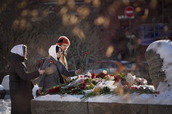 19.02.2024, Russland, Moskau: Jugendliche legen Blumen nieder, um Nawalny die letzte Ehre zu erweisen. Das Denkmal ist ein großer Felsblock von den Solowezki-Inseln, wo das erste Lager des politischen ...