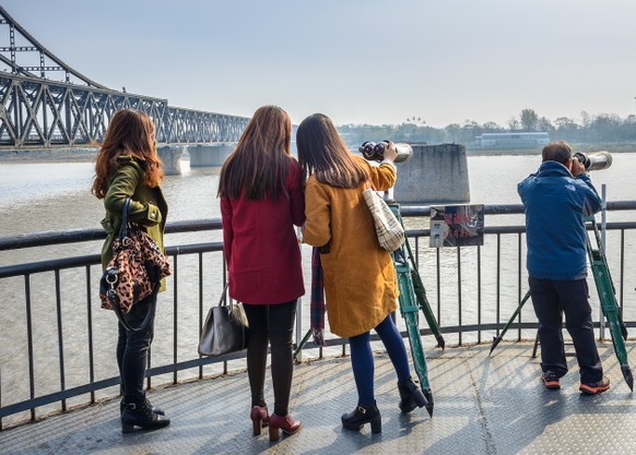 Dandong, China - November 8, 2014: The end of the Yalu River Broken Bridge. People are looking through the telescope. Located in middle of Yalu River, Dandong, Liaoning, China.