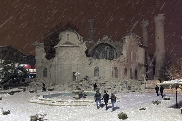 06.02.2023, Türkei, Malatya: Menschen gehen neben einer durch ein Erdbeben zerstörten Moschee. Ein starkes Erdbeben hat im Südosten der Türkei und in Syrien mehrere Gebäude zum Einsturz gebracht, und  ...