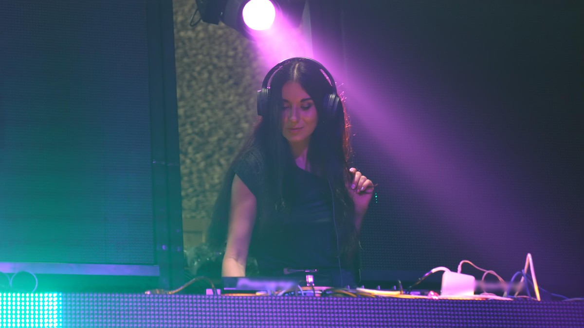DJ on stage in disco night club mixing techno music beat . Nightlife and dance party .