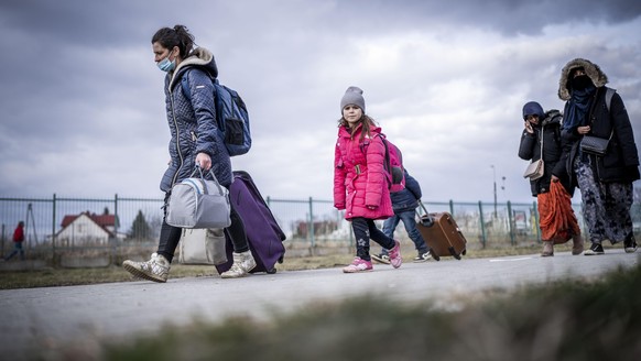 Geflüchtete aus der Ukraine gehen nach ihrem Grenzübertritt in Polen durch das polnische Grenzgebiet. Zahlreiche Menschen verlassen nach dem Angriff Russlands auf die Ukraine das Land. Viele flüchten ...
