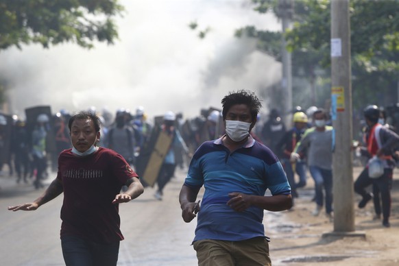 Anti-coup protesters run away when police security forces try to disperse them with tear gas in Mandalay, Myanmar, Saturday, March 13, 2021. Myanmar's military seized power Feb. 1, hours before the se ...