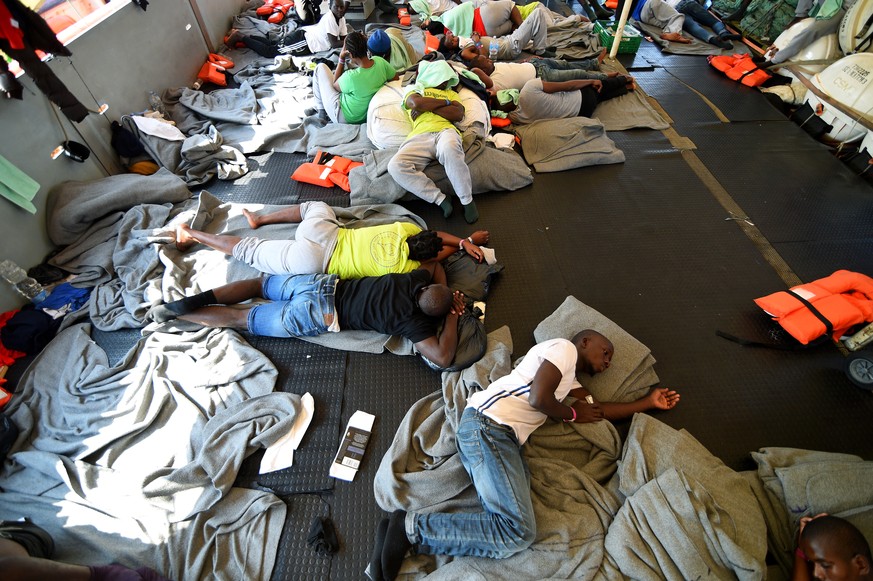 Migrants lie on board the rescue ship Sea-Watch 3 as it remains blocked one mile outside the port of Lampedusa, Italy, June 27, 2019. REUTERS/Guglielmo Mangiapane