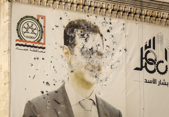 An image of Syrian President Bashar Assad, riddled with bullets, is seen on the facade of the provincial government office in the aftermath of the opposition&#039;s takeover of Hama, Syria, Friday, De ...