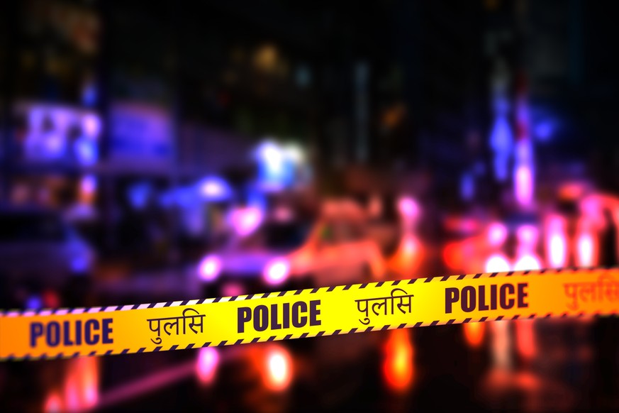 A night time street scene with focus on safety Police tape in Hindi. Hindi is spoke in Uttar Pradesh, Haryana, Himachal Pradesh and the capital Delhi in North India; Bihar and Jharkhand in Eastern Ind ...