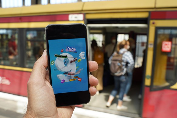 Ein Smartphone, auf dem eine Werbung für das 9-Euro-Ticket zu sehen ist, wird vor eine S-Bahn gehalten. Die Sondertickets sollen im Juni, Juli und August bundesweit Fahrten im Nah- und Regionalverkehr ...