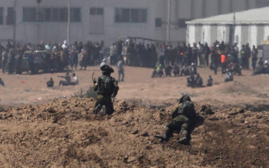 Israelische Soldaten (Vordergrund) und palästinensische Demonstranten (Hintergrund) an der Grenze zwischen Gaza und Israel.