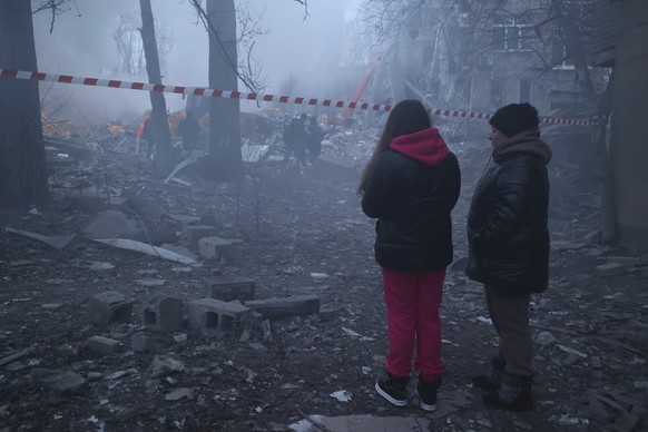 16.01.2023, Ukraine, Donezk: Anwohner stehen in der Nähe der Trümmer eines durch Beschuss zerstörten Einkaufszentrums. Foto: Alexei Alexandrov/AP/dpa +++ dpa-Bildfunk +++