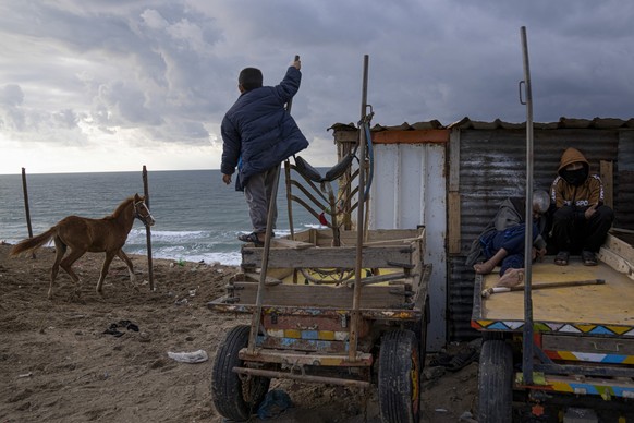 Palestinians sit in front of their house next to the beach during a rainy day in Dier al-Balah, central Gaza Strip, Saturday, Feb. 4, 2023. (AP Photo/Fatima Shbair)