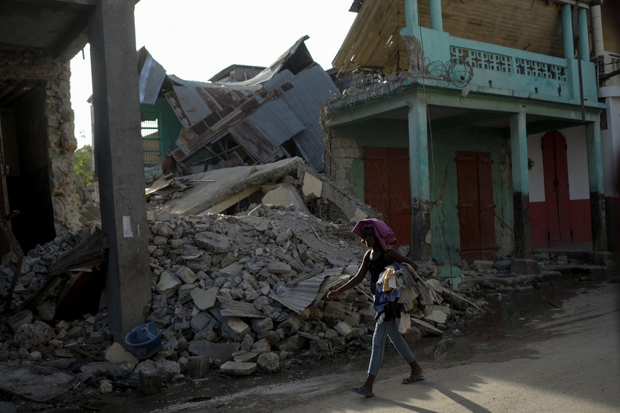 Eine Frau geht an einem eingestürzten Gebäude in Jeremie vorbei.