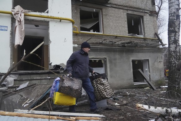 02.01.2024, Ukraine, Charkiw: Ein Mann trägt seine Habseligkeiten aus einem durch einen russischen Raketenangriff beschädigten Wohnhaus. Foto: Andrii Marienko/AP/dpa +++ dpa-Bildfunk +++