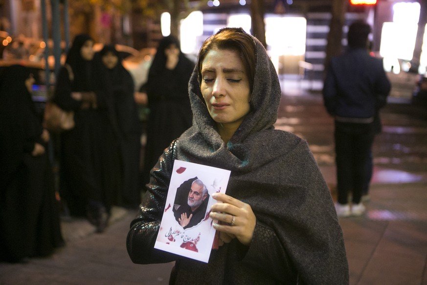 Ein Frau hält ein Bild von Soleimani in den Händen und trauert.