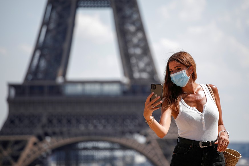 FILE PHOTO: A woman wears a protective face mask at the Trocadero square near the Eiffel Tower in Paris as France reinforces mask-wearing as part of efforts to curb a resurgence of the coronavirus dis ...