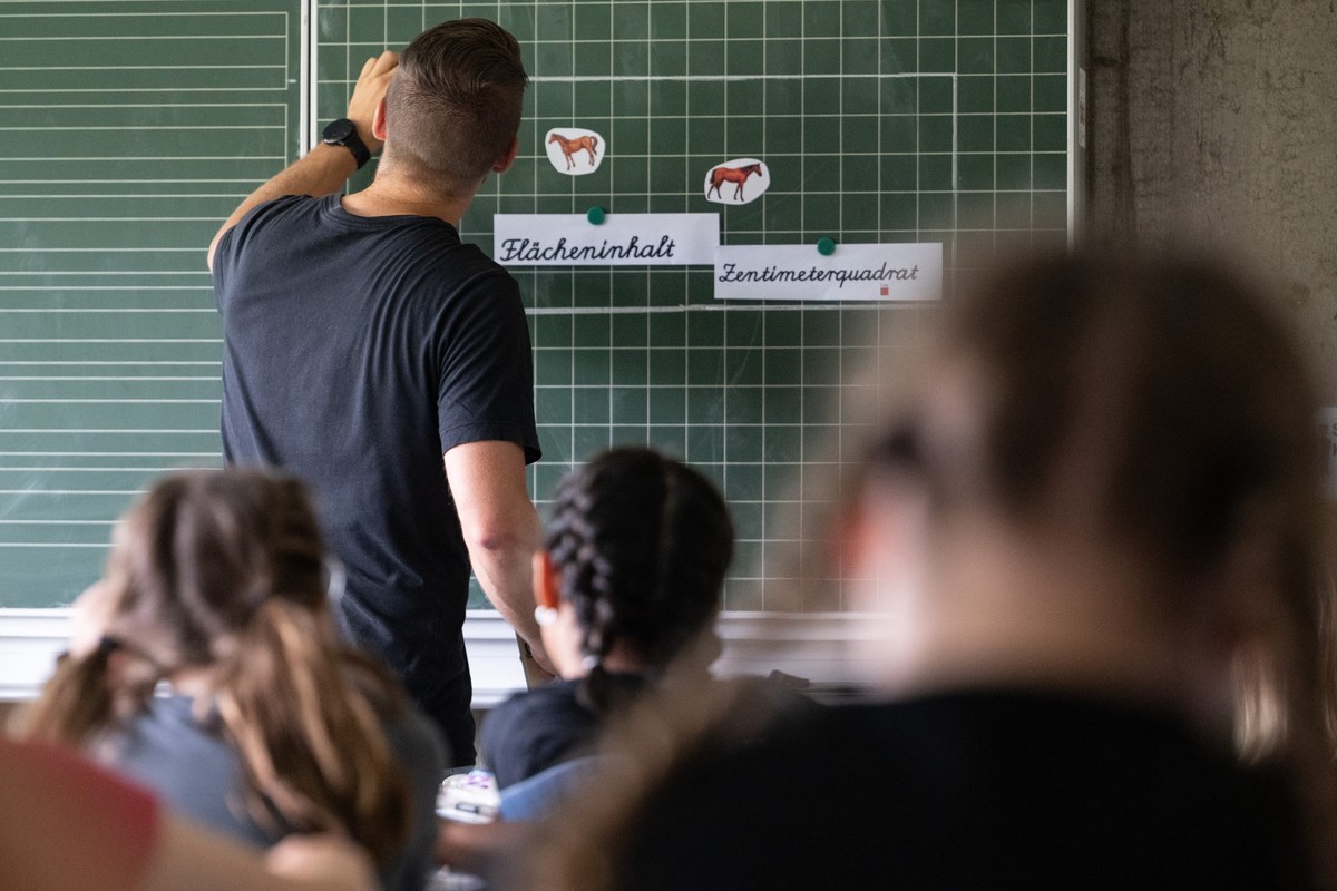 ARCHIV - 27.06.2024, Baden-Württemberg, Neckartailfingen: Ein Lehrer macht im Unterricht einer vierten Klasse einer Grundschule einen Tafelanschrieb, während an der Tafel Zettel mit der Aufschrift «Fl ...