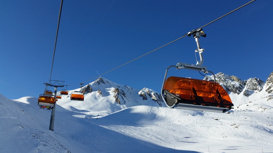 a high capacity chairlift taking skiers up the snow covered mountains and ski field of Ischgl, Austria.