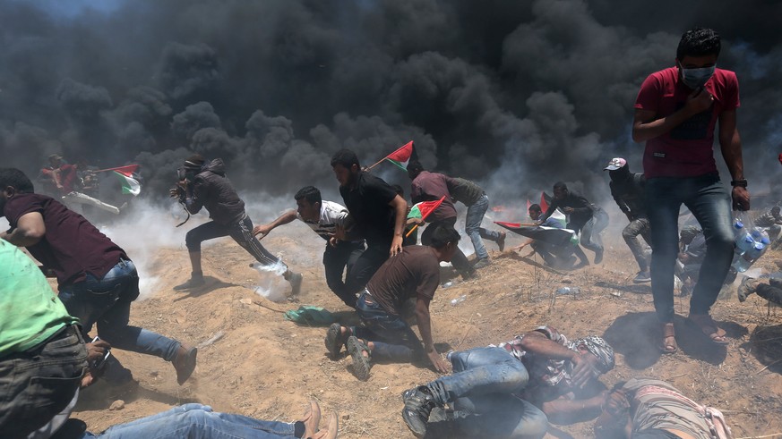 Palestinian demonstrators run for cover from Israeli fire and tear gas during a protest against U.S. embassy move to Jerusalem and ahead of the 70th anniversary of Nakba, at the Israel-Gaza border in  ...