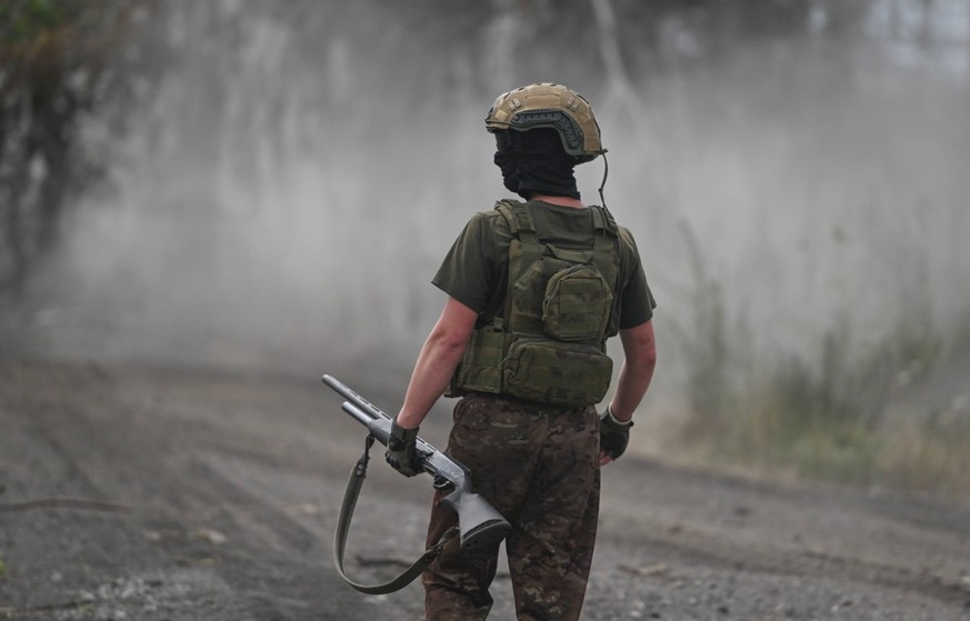 Russia Ukraine Military Operation Artillery Units 8733268 23.07.2024 A Russian serviceman of the Central Military District with a hunting rifle walks in the Avdeevka sector of the frontline of Russias ...