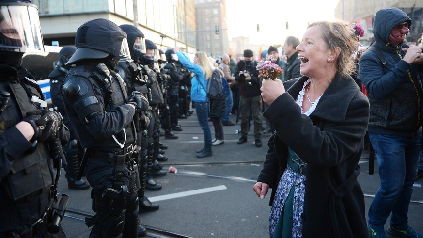 Demonstration der Querdenken-Bewegung gegen die Anti-Corona-Maßnahmen der Bundesregierung, Leipzig, Augustusplatz, 7.11.2020 Eine Demonstrantin steht vor einer Polizeikette und hält Blumen in der Hand ...