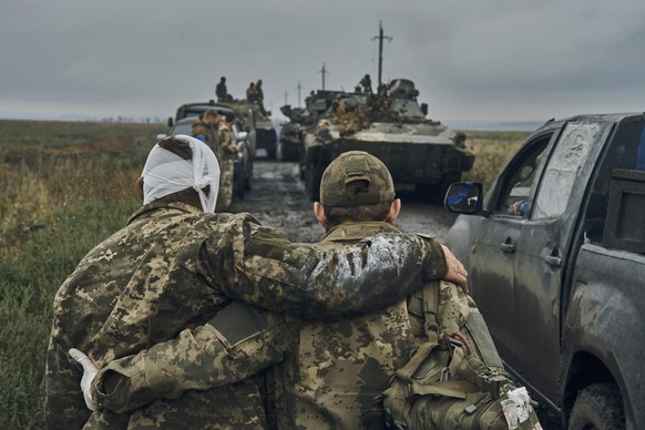 Ein ukrainischer Soldat hilft einem verwundeten Kameraden auf der Straße in dem befreiten Gebiet in der Region Charkiw