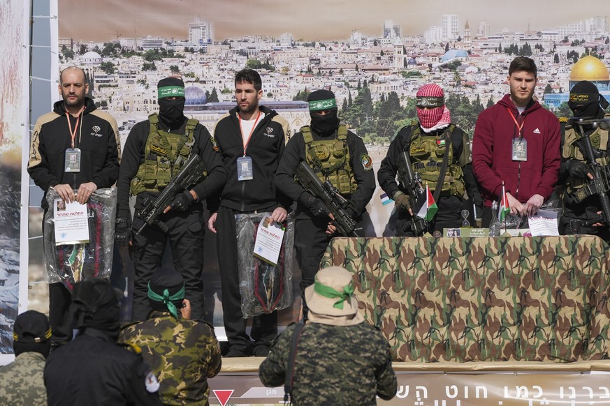 15.02.2025, Palästinensische Gebiete, Chan Junis: Die israelischen Geiseln Iair Horn (l), Sagui Dekel Chen (Mitte links) und Alexander Trufanov (r) werden von Kämpfern der Hamas und des Islamischen Ds ...