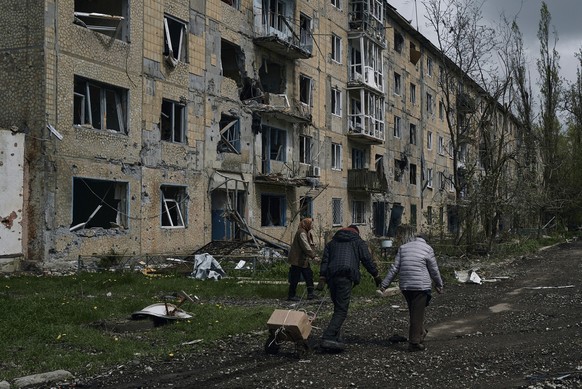 28.04.2023, Ukraine, Awdijiwka: Anwohner tragen ihre Habseligkeiten, während sie ihr Haus in Awdijiwka in der Region Donezk verlassen. Foto: LIBKOS/AP/dpa +++ dpa-Bildfunk +++