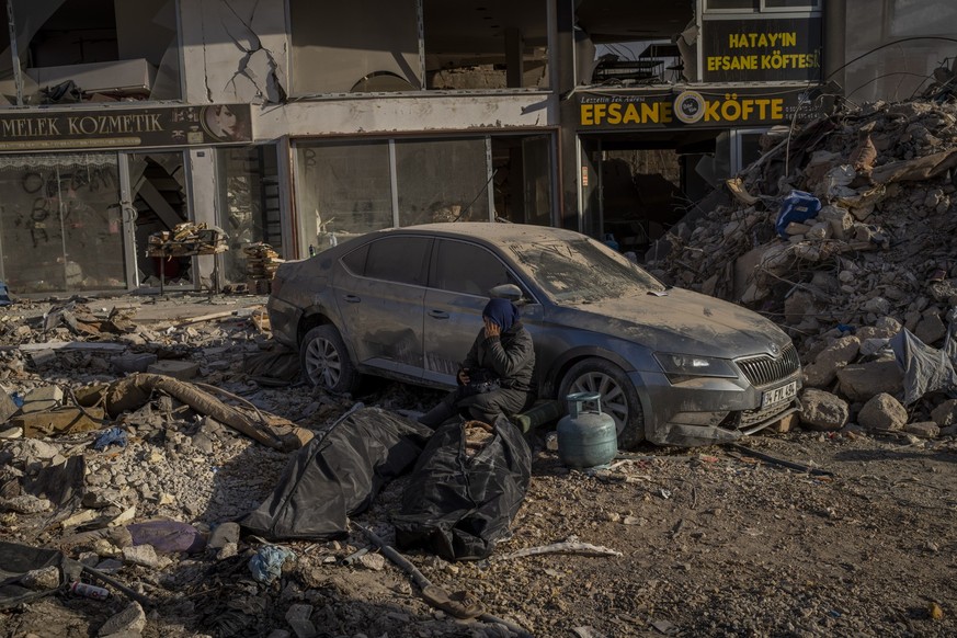 A woman sits next to bodies that were pulled from the rubble of a destroyed building in Antakya, southeastern Turkey, Wednesday, Feb. 15, 2023. The earthquakes that killed more than 39,000 people in s ...