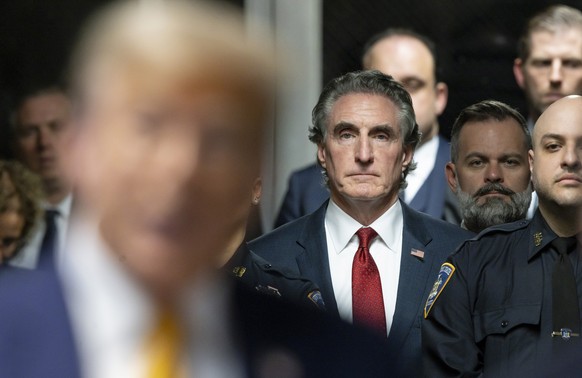 Republican North Dakota Governor Doug Burgum, back center, listens as former President Donald Trump, left, talks to reporters outside the courtroom at the end of the day of his trial at Manhattan crim ...