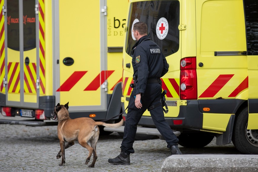 24.10.2023, Pulsnitz: Ein Polizist läuft nach einer eingegangen Drohung mit einem Hund vor einer Grund- und Oberschule im ostsächsischen Pulsnitz. Auch andere Schulen in Sachsen waren betroffen. Die S ...