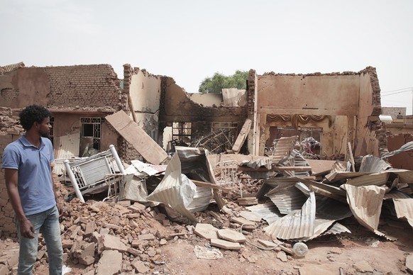25.04.2023, Sudan, Khartum: Ein Mann geht an einem Haus vorbei, das bei den jüngsten Kämpfen getroffen wurde. Im Sudan sind vor mehr als einer Woche schwere Kämpfe zwischen dem Militär und Paramilitär ...