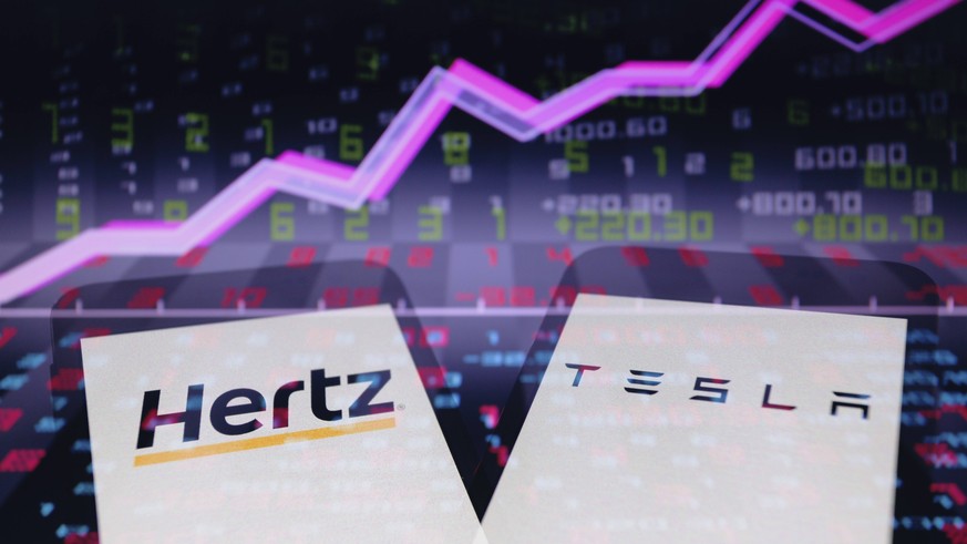 October 25, 2021, Asuncion, Paraguay: In-camera multiple exposure image shows logos of Hertz and Tesla on smartphone backdropped by abstract presentation of line chart and numbers on screen. Rental ca ...