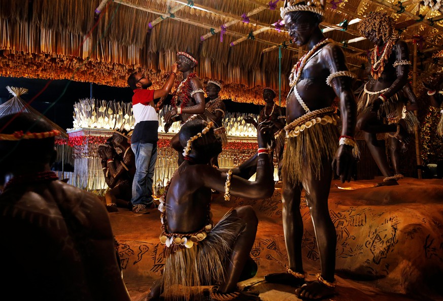 A man applies finishing touches on a sculpture of a man from the Jarawa tribe, indigenous people of the Andaman Islands, which will be used to decorate a pandal, or a temporary platform, for the upcom ...