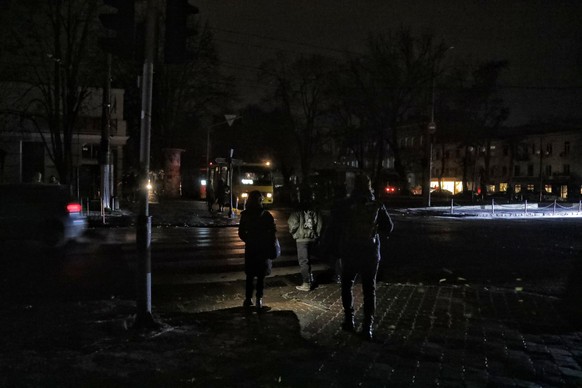 05.12.2022, Ukraine, Odessa: Fußgänger halten sich an einer Kreuzung auf einer dunklen Straße auf, da die Stadt von Stromausfällen betroffen ist, nachdem der massive Raketenangriff russischer Truppen  ...