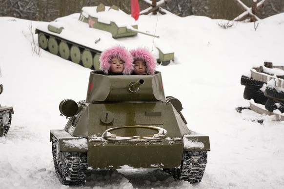04.02.2023, Russland, St. Petersburg: Kinder fahren auf einem Modell des sowjetischen T-34-Panzers aus der Zeit des Zweiten Weltkriegs während eines militärhistorischen Festes im Familienpark für hist ...