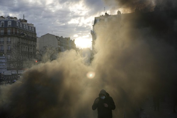 28.03.2023, Frankreich, Paris: Ein Mann geht nach einer Demonstration durch eine Rauchwolke. Eine neue Runde von Streiks und Demonstrationen ist gegen die unpopulären Rentenreformen geplant, die vor a ...