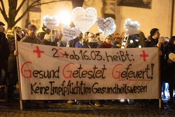 Impfgegner und Kritiker der Corona-Maßnahmen stehen während eines Protest gegen Corona-Maßnahmen und eine mögliche Impfpflicht in Deutschland mit einem Transparent mit der Aufschrift „2G+ ab 16.03. he ...