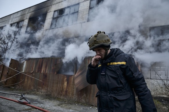 05.02.2023, Ukraine, Cherson: Ein Feuerwehrmann raucht, während er nach dem Löschen eines Feuers, welches durch russischen Beschuss auf ein Industriegebiets entstand, eine Pause einlegt. Foto: -/LIBKO ...