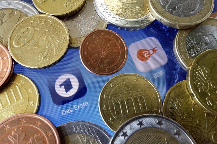 ARCHIV - 16.02.2015, Berlin: Euromünzen liegen neben den Logos der Apps von ARD und ZDF. Das Bundesverfassungsgericht verkündet an diesem Donnerstag seine Entscheidung über Verfassungsbeschwerden der  ...