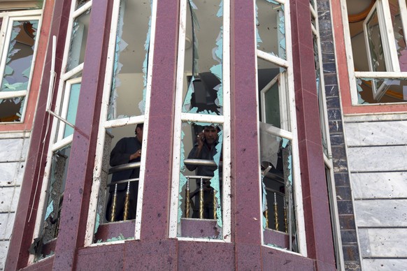 Afghans are seen through shattered windows of a voter registration center which was attacked by a suicide bomber in Kabul, Afghanistan, Sunday, April 22, 2018. Gen. Daud Amin, the Kabul police chief,  ...