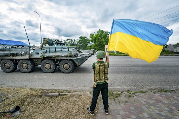 June 27, 2023, Sloviansk, Donetsk, Ukraine: A boy waves a Ukrainian flag as an armored vehicle from the Ukrainian army goes to the Bakhmut frontlines during the Russian invasion of Ukraine. Sloviansk  ...
