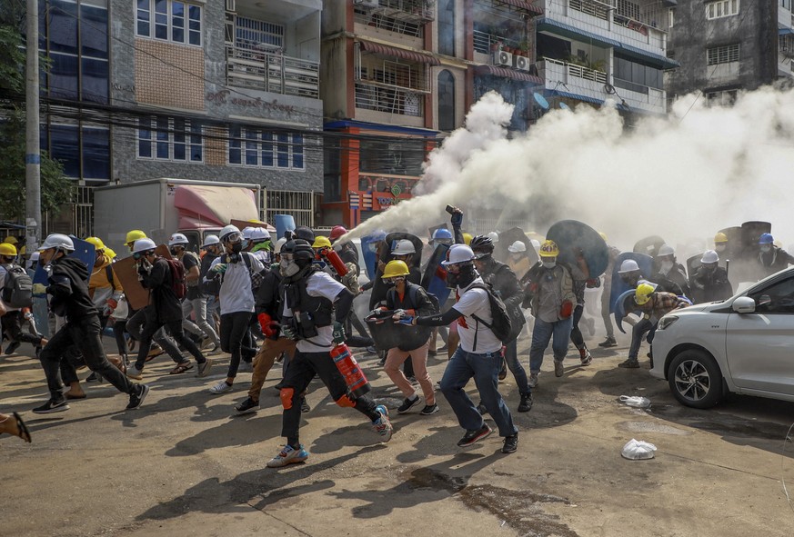 Anti-coup protesters run as one of them discharges a fire extinguisher to counter the impact of tear gas fired by riot policemen in Yangon, Myanmar, Wednesday, March 3, 2021. Demonstrators in Myanmar  ...