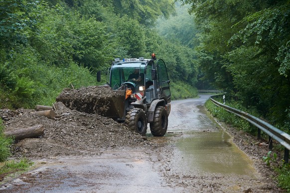 Bergungskräfte räumen mit Hilfe eines Radladers Erde von der Landesstrasse 113 zwischen Isenburg und Thalhausen (Rheinland-Pfalz): Ein Gewitter hatte mehrere Erdrutsche ausgelöst.