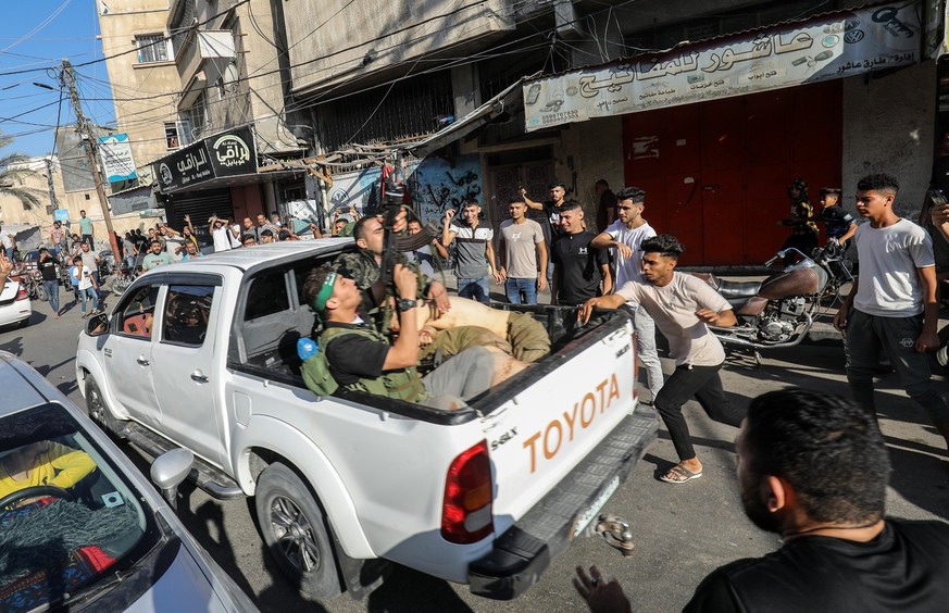 07.10.2023, Palästinensische Gebiete, Khan Yunis: Militante Palästinenser umringen einen Lastwagen, der angeblich einen gefangenen Israeli transportiert. Die islamistische Hamas hat einen großangelegt ...