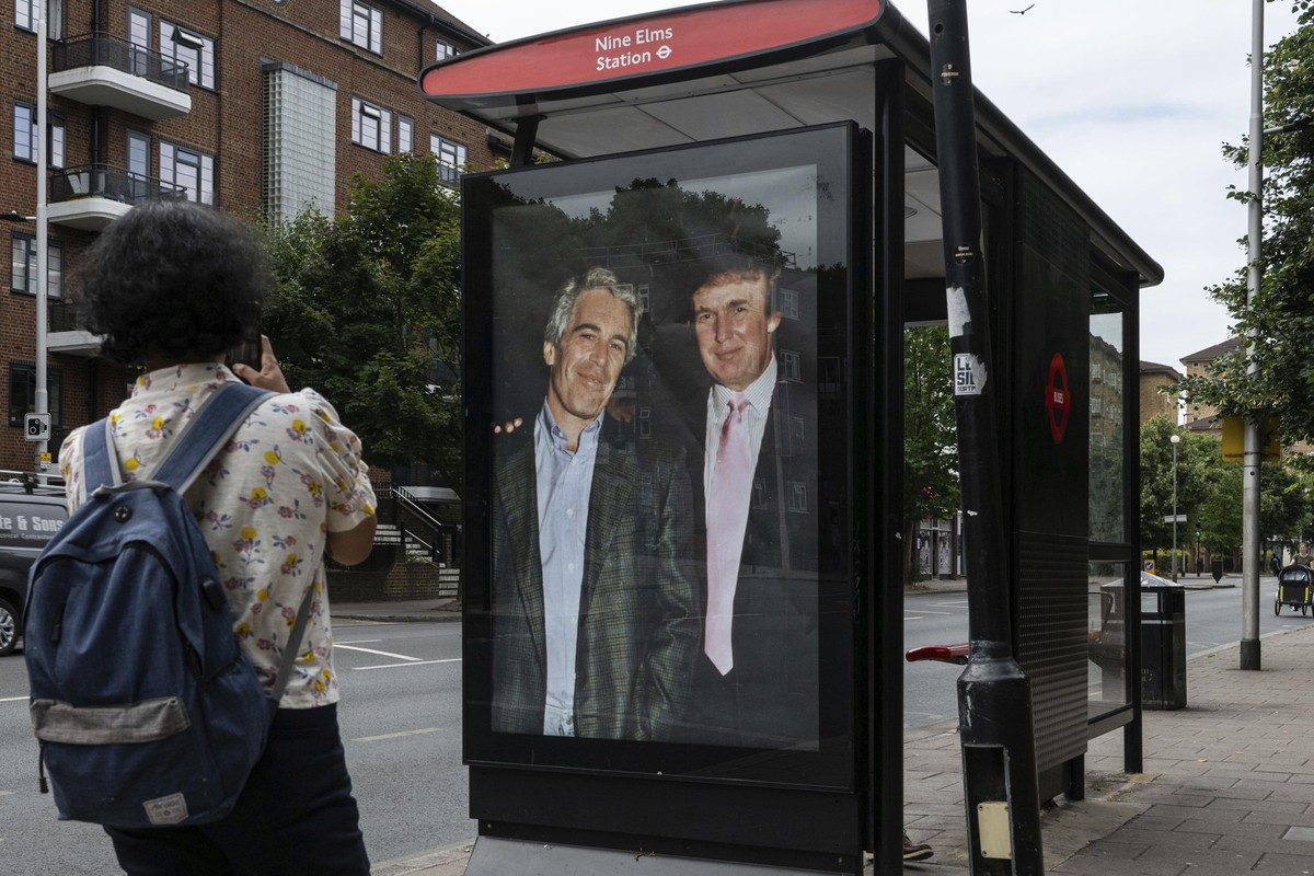 Commuters walk past a bus stop near Nine Elms Station as activists put up a poster showing President Donald Trump and Jeffrey Epstein near the US Embassy in London, Thursday, July 17, 2025.(AP Photo/T ...