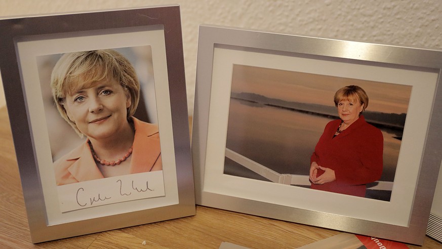 30.11.2018, Nordrhein-Westfalen, Attendorn: Ein Foto von Ursula Wanecki (r), Merkel Double, steht in ihrer Wohnung neben einer Autogrammkarte der Bundeskanzlerin (l) auf dem Schreibtisch. Foto: Oliver ...