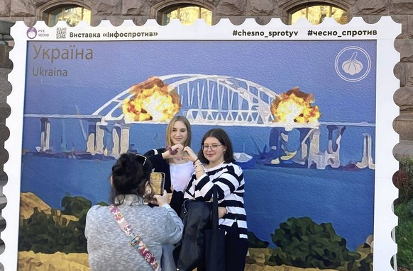 Stamp-like artwork featuring Crimea bridge blast People pose in Kyiv on Oct. 8, 2022, for a photo in front of an oversized stamp featuring an artist s impression of an explosion earlier that day which ...