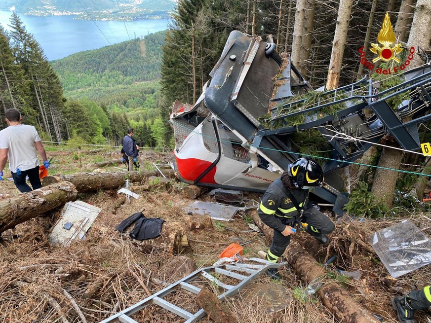 HANDOUT - 23.05.2021, Italien, Stresa: Rettungshelfer arbeiten am Wrack einer Seilbahngondel, nachdem diese abgest
