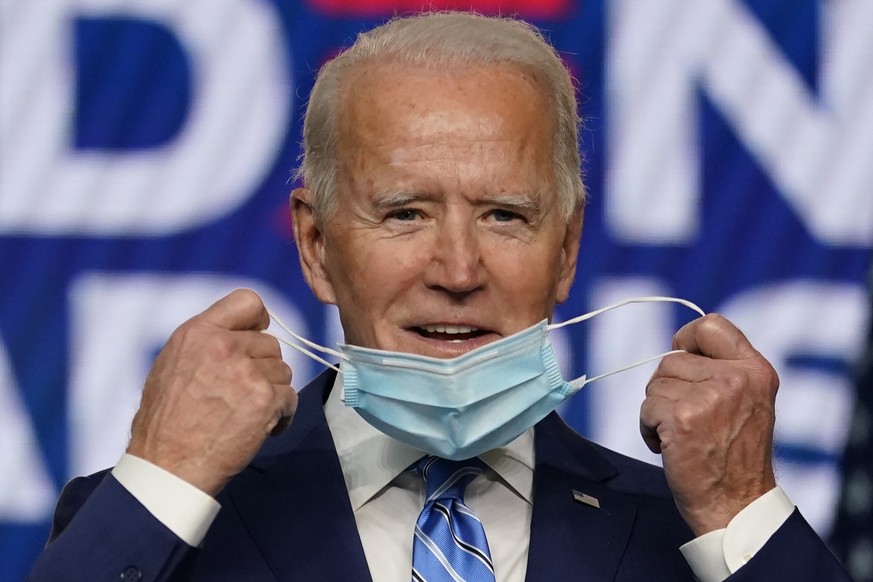 Democratic presidential candidate former Vice President Joe Biden takes off his face mask as he arrives to speak, Wednesday, Nov. 4, 2020, in Wilmington, Del. (AP Photo/Carolyn Kaster)