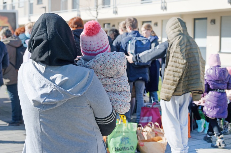 ARCHIV - 03.03.2022, Nordrhein-Westfalen, Köln: Geflüchtete aus der Ukraine stehen vor den Gebäuden einer Flüchtlingsunterkunft. Nordrhein-Westfalen plant derzeit nicht, Bezahlkarten einzuführen, um B ...