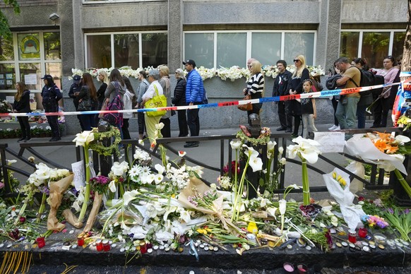 05.05.2023, Serbien, Belgrad: Menschen warten darauf, sich in das Kondolenzbuch vor der Vladimir-Ribnikar-Schule einzutragen. Nach einem Angriff mit acht Toten nahe Belgrad hat die Polizei den mutmaßl ...
